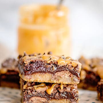 a stack of brookies on a white and blue polkadotted fabric with a jar of caramel behind it