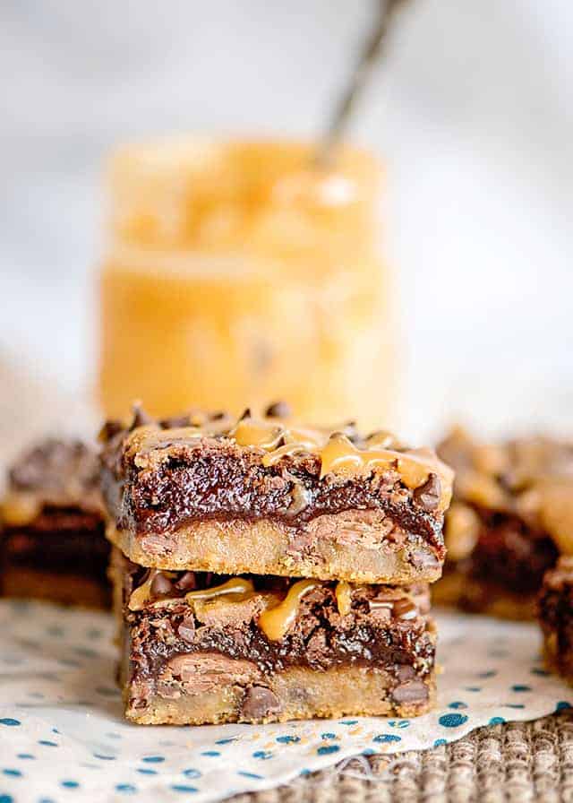 a stack of brookies on a white and blue polkadotted fabric with a jar of caramel behind it