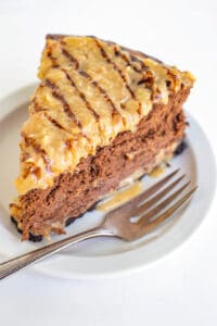 slice of cheesecake on a small white plate with a fork sitting next to the cheesecake