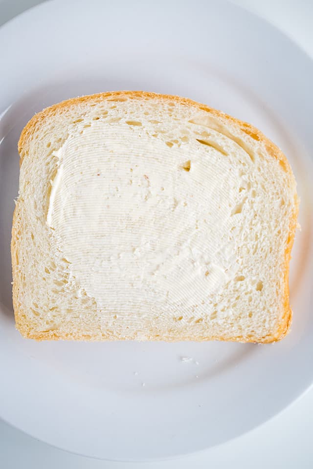 slice of homemade bread on a small white plate with butter spread on it