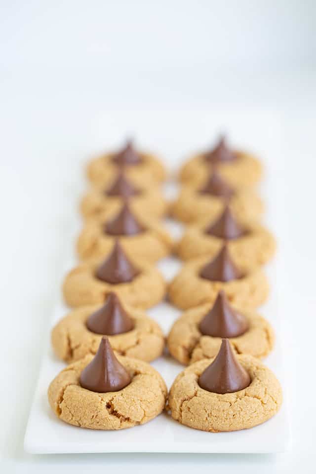 two rows of peanut butter kiss cookies on a long white platter with a white background