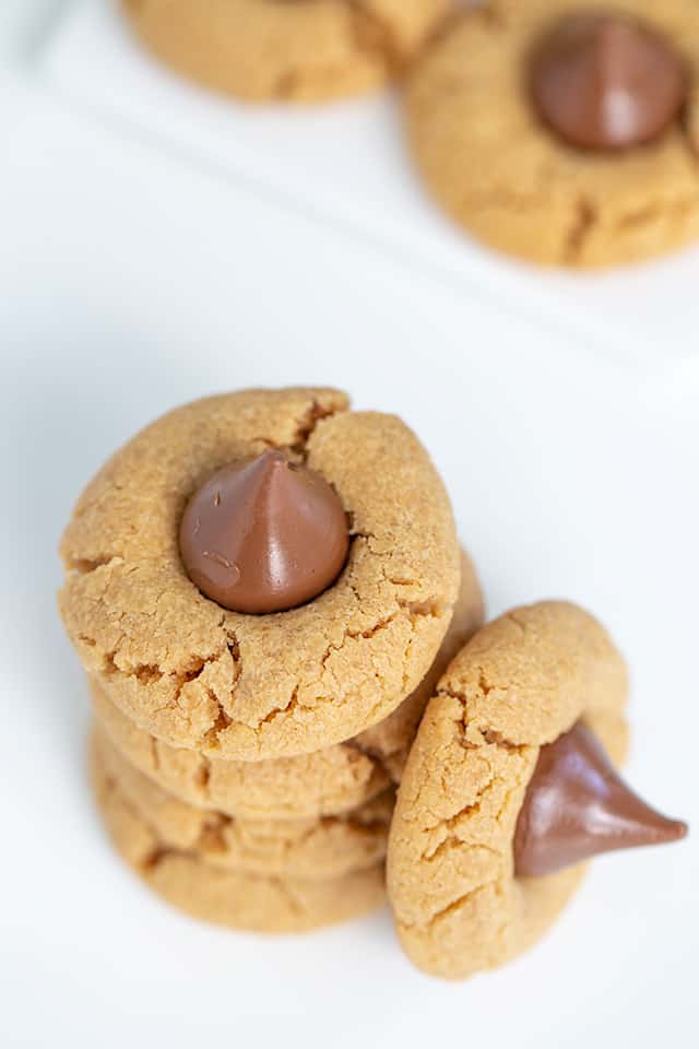 overhead closeup of stacked peanut butter blossom cookies on a white surface