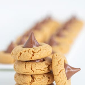 Stack of Peanut Butter Blossom Cookies with another cookie on its side leaned against the stack