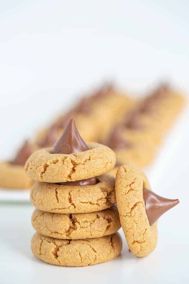 Stack of Peanut Butter Blossom Cookies with another cookie on its side leaned against the stack