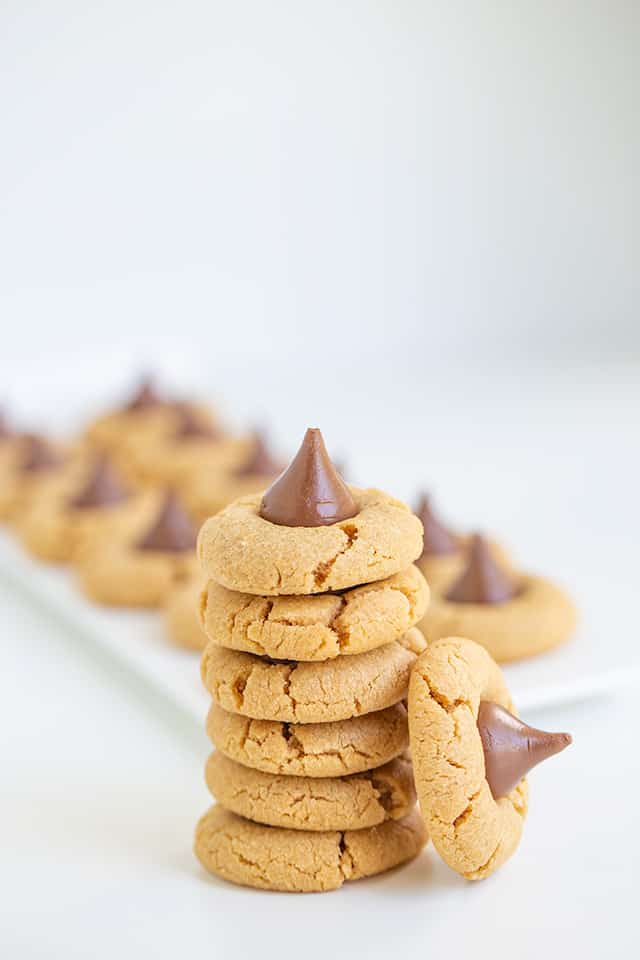 tall stack of Hershey Kiss Cookies with a platter of cookies behind it