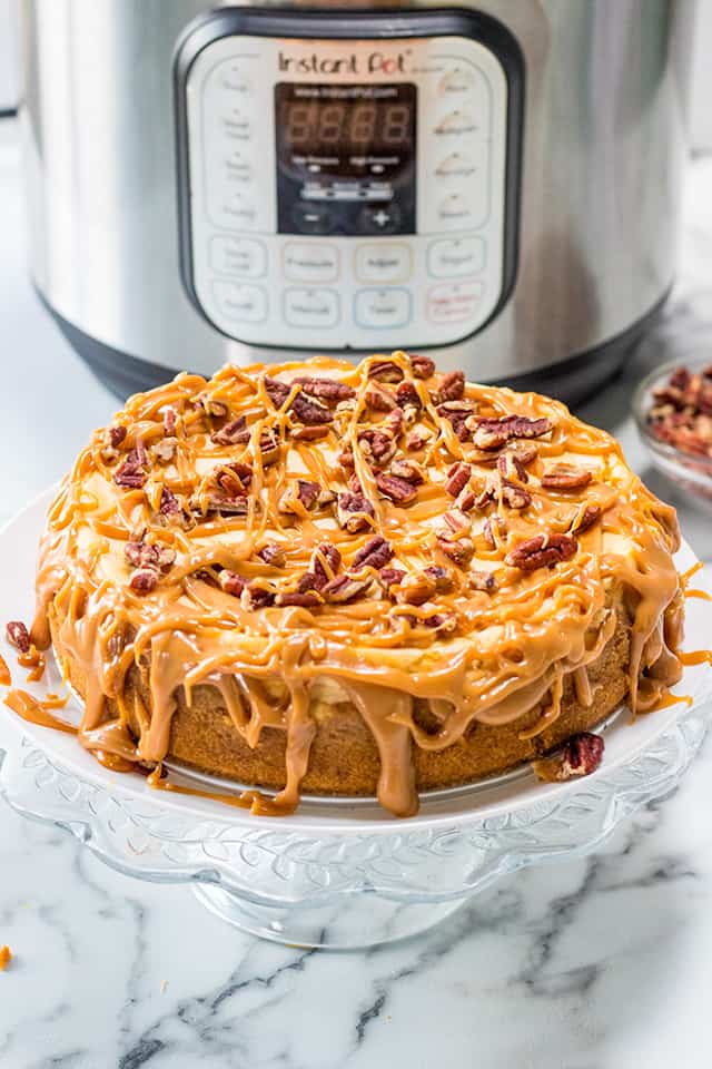 IP Salted Caramel Cheesecake on a glass cake pan with Instant Pot behind it