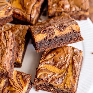 pumpkin brownies on a white plate with one propped up on another showing off the side of the brownie