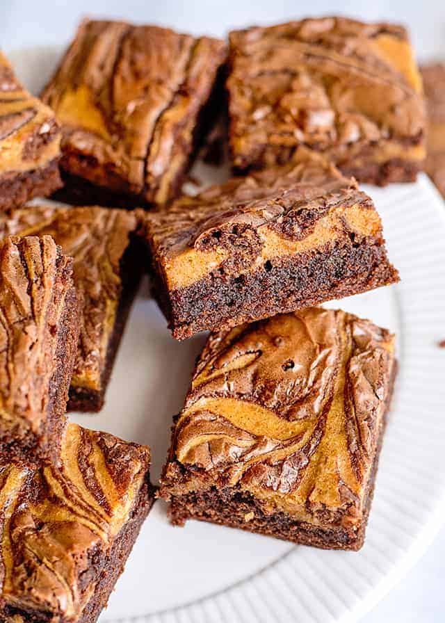 pumpkin brownies on a white plate with one propped up on another showing off the side of the brownie