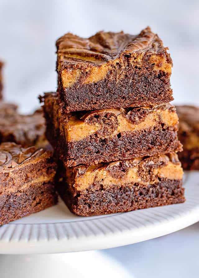 3 pumpkin brownies stacked on a white cake plate