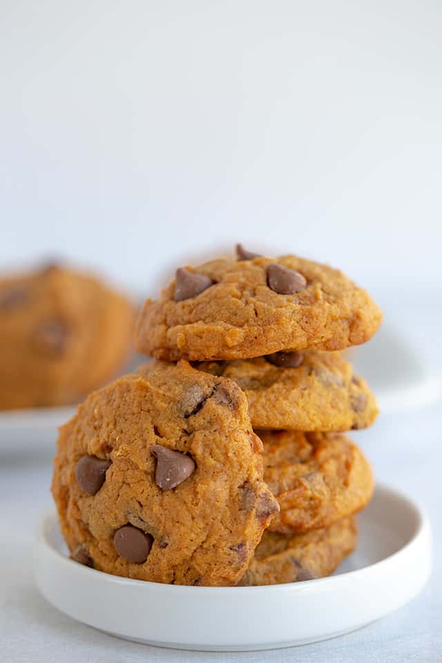 stack of pumpkin pudding cookies with a cookie leaned against them on a white plate
