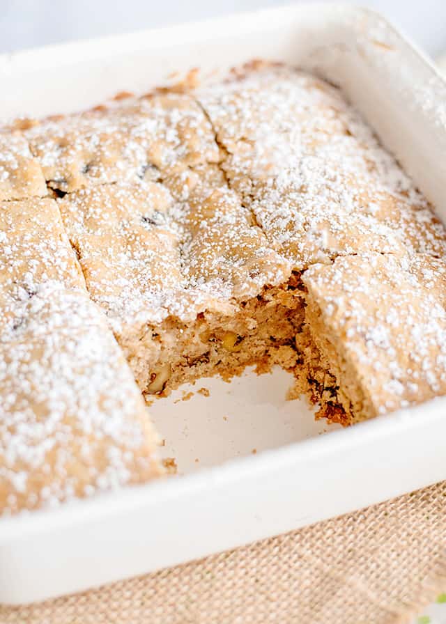 a white pan full of sliced cake with a slice missing