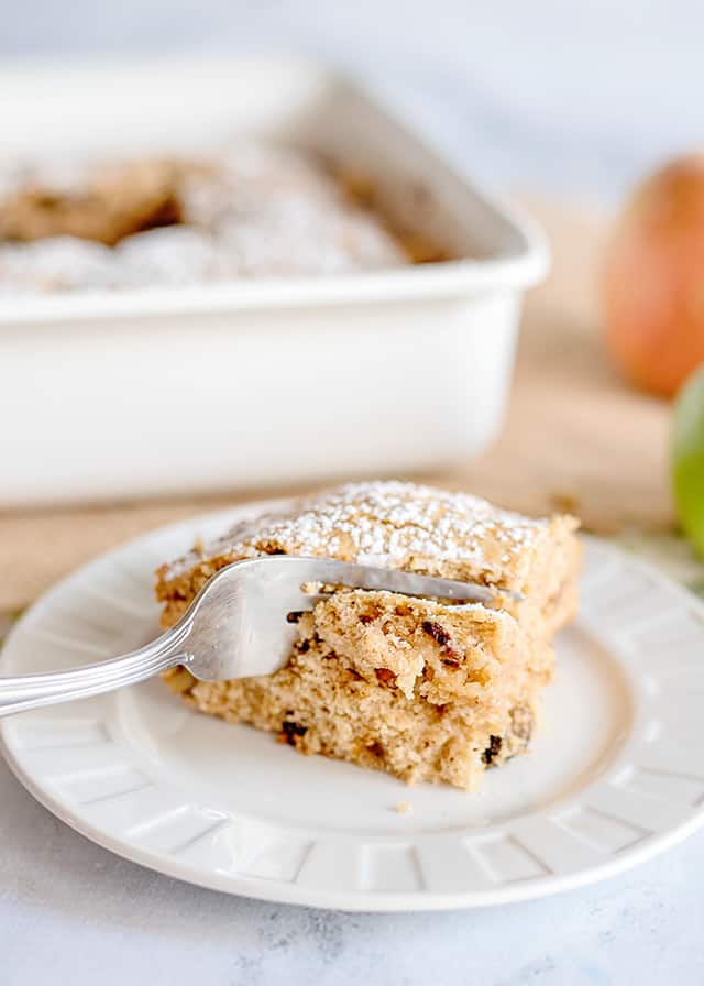 applesauce cake on a plate with a fork in it cutting a piece