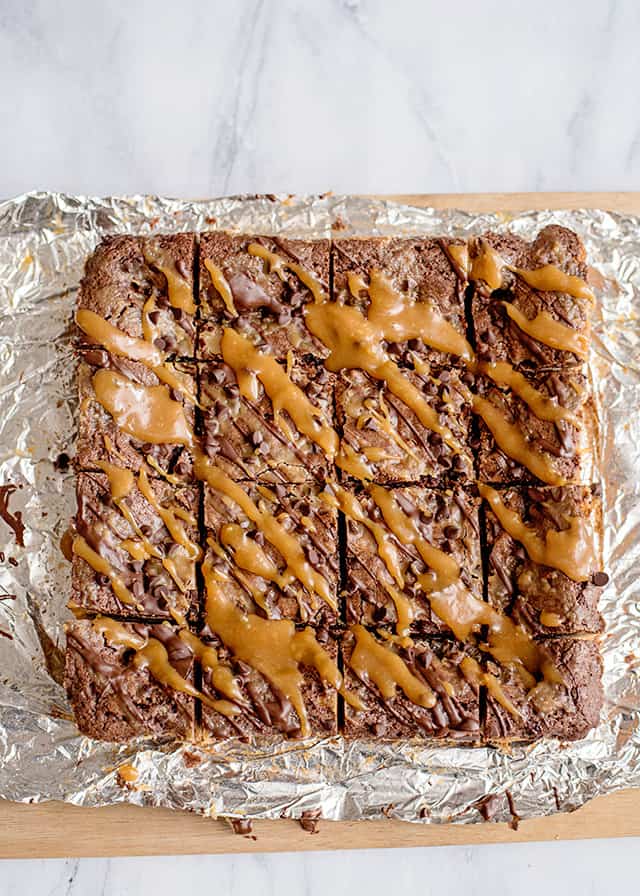 cut caramel brookies on tin foil on a cutting board