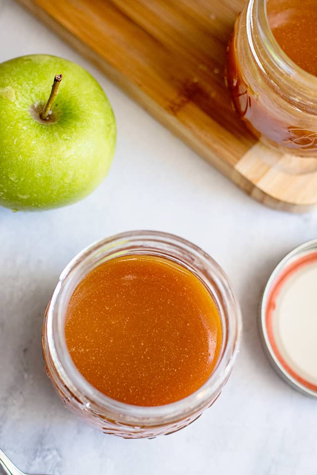 overhead photo of jars of caramel sauce with an apple