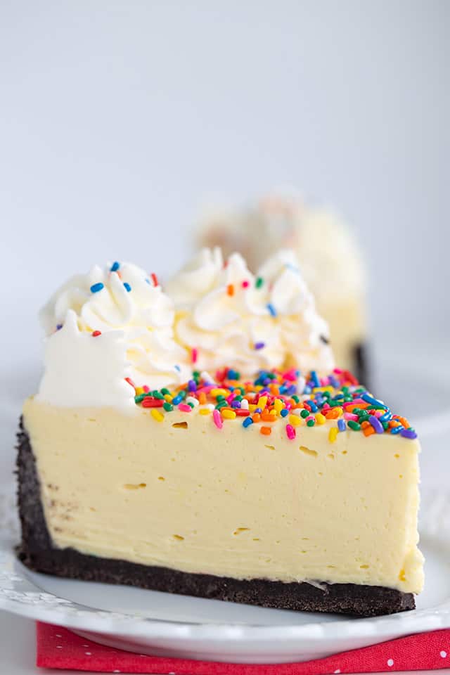 close up of no bake birthday cheesecake on a white plate with pink polkadot fabric