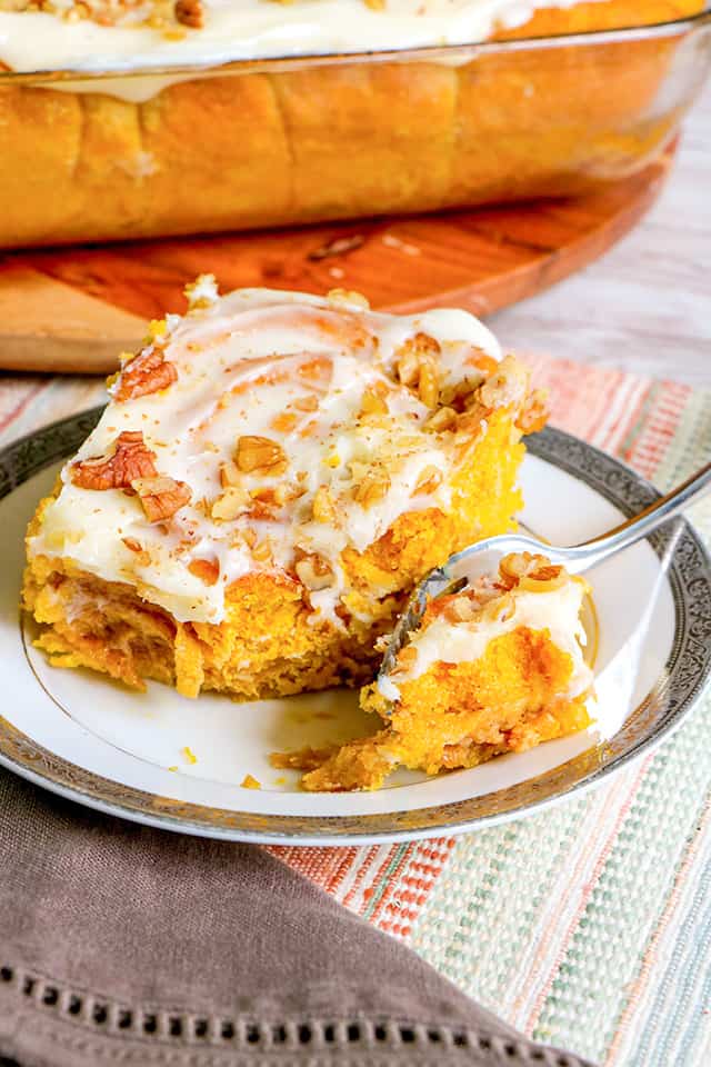 cinnamon roll on a small plate with a fork on the plate