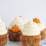 pumpkin cupcakes with swirls of frosting on a wavy white cake plate