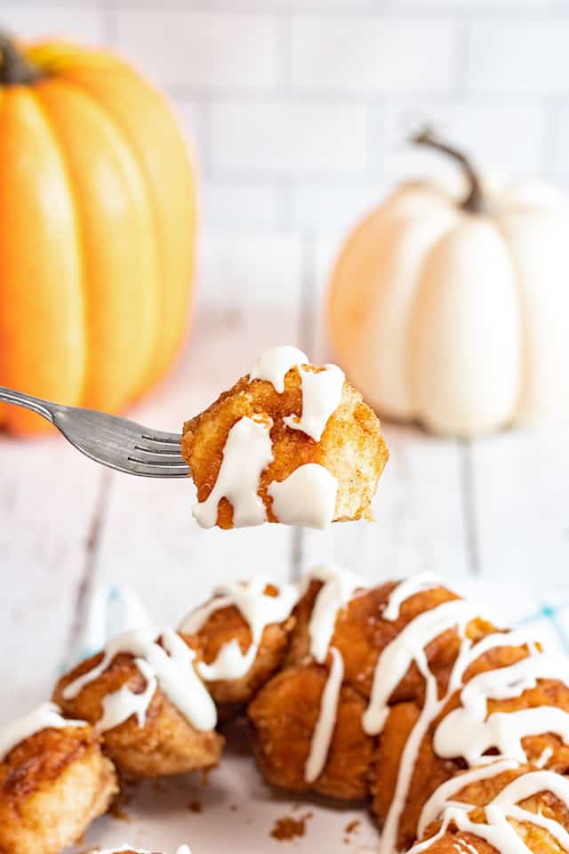 fork full of monkey bread with pumpkins behind it