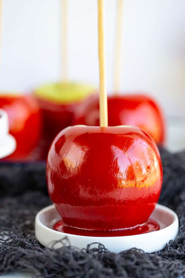 red candy apple on a white plate with black netting under it