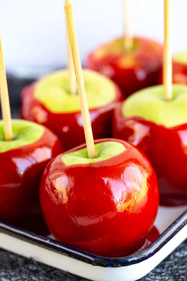 a small black rimmed white pan full of candy apples