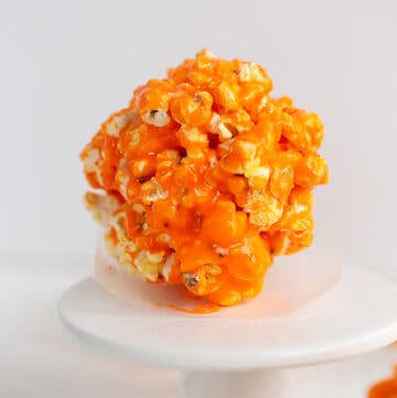 popcorn ball sitting on a piece of parchment paper on a cupcake stand