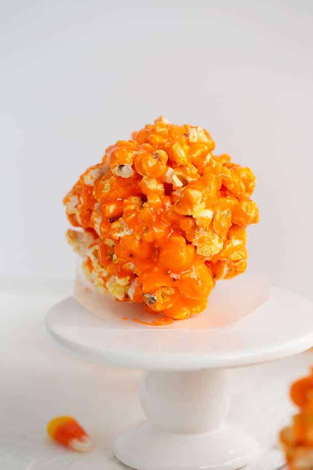 popcorn ball sitting on a piece of parchment paper on a cupcake stand
