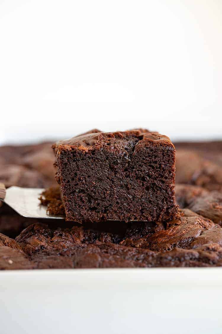 slice of earthquake cake on a spatula over top of the cake in the pan