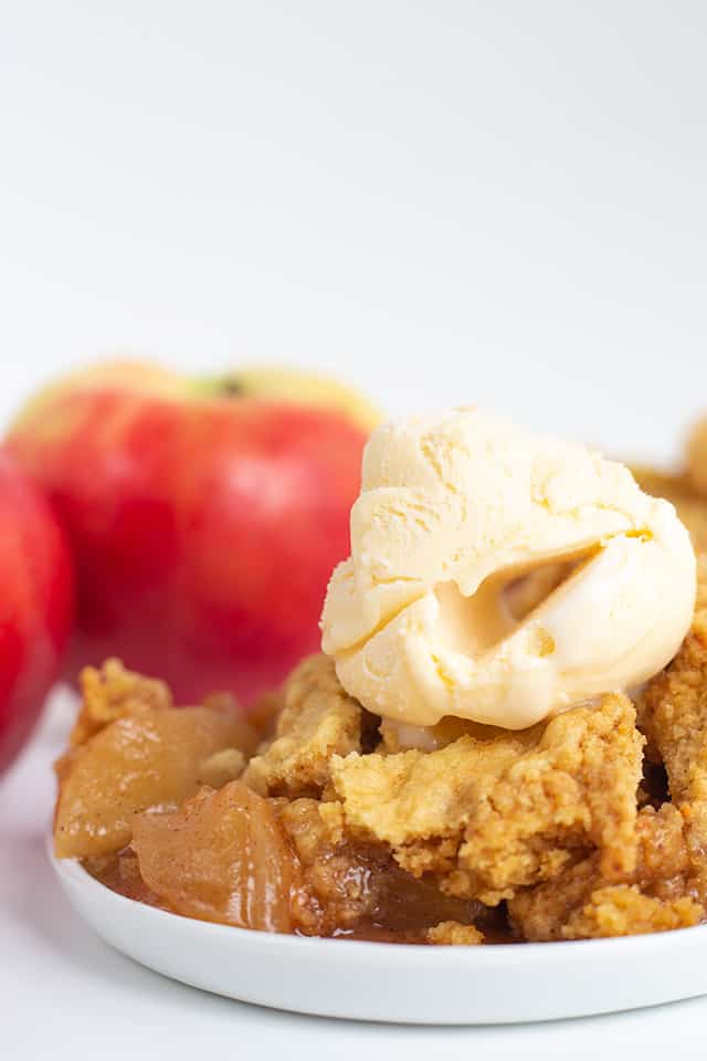 dessert plate full of crockpot apple cobbler with ice cream on top