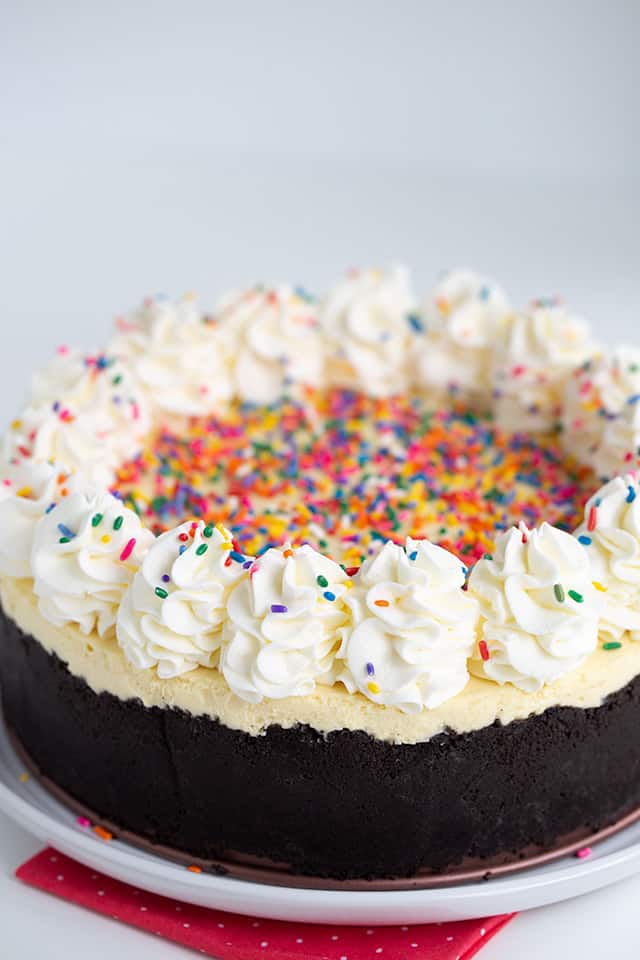 whole cheesecake on a white plate with pink fabric and white background