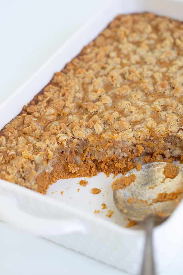 white baking dish with a serving spoon and pumpkin crisp