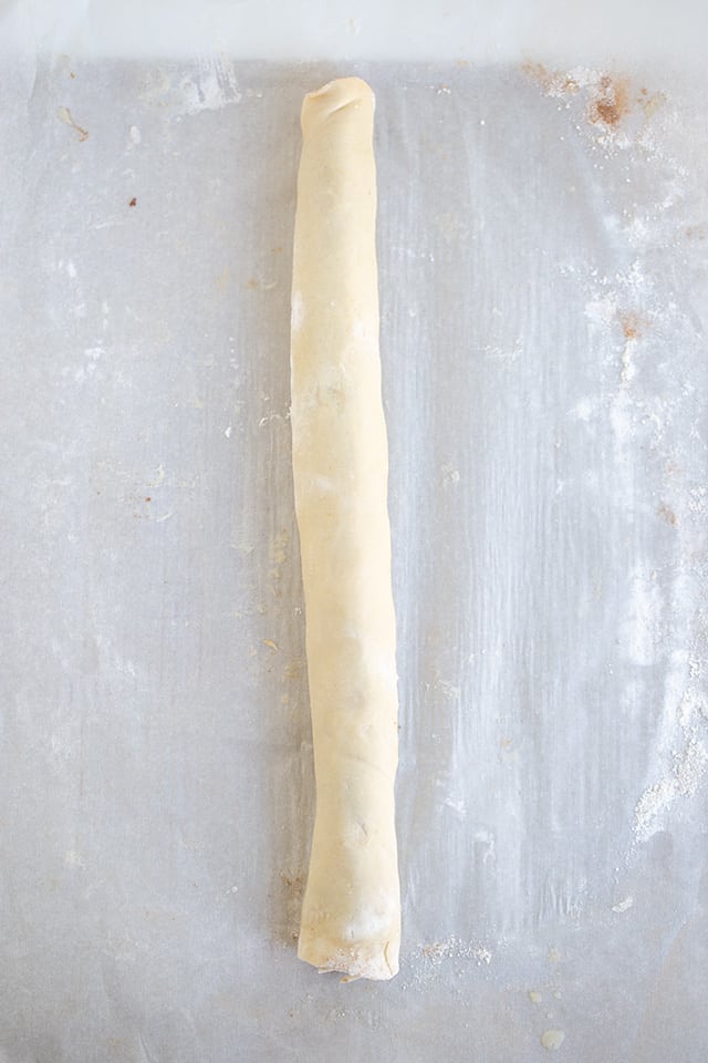 A rolled up pie crust on a piece of parchment paper