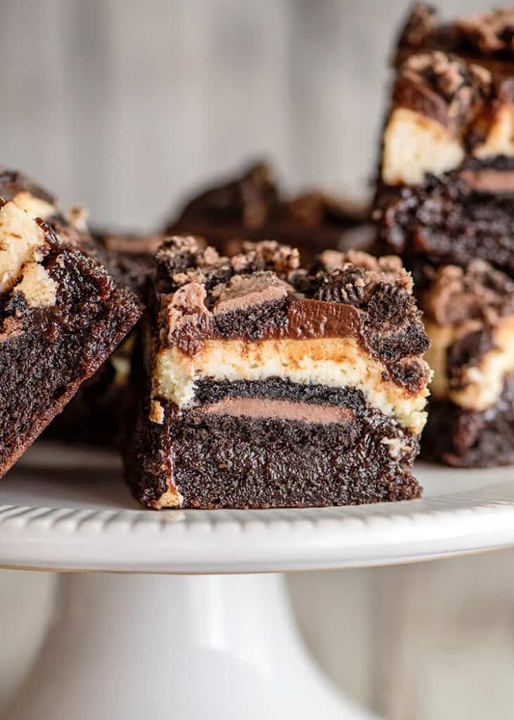 a layered brownie bar on a white plate with other bars around it