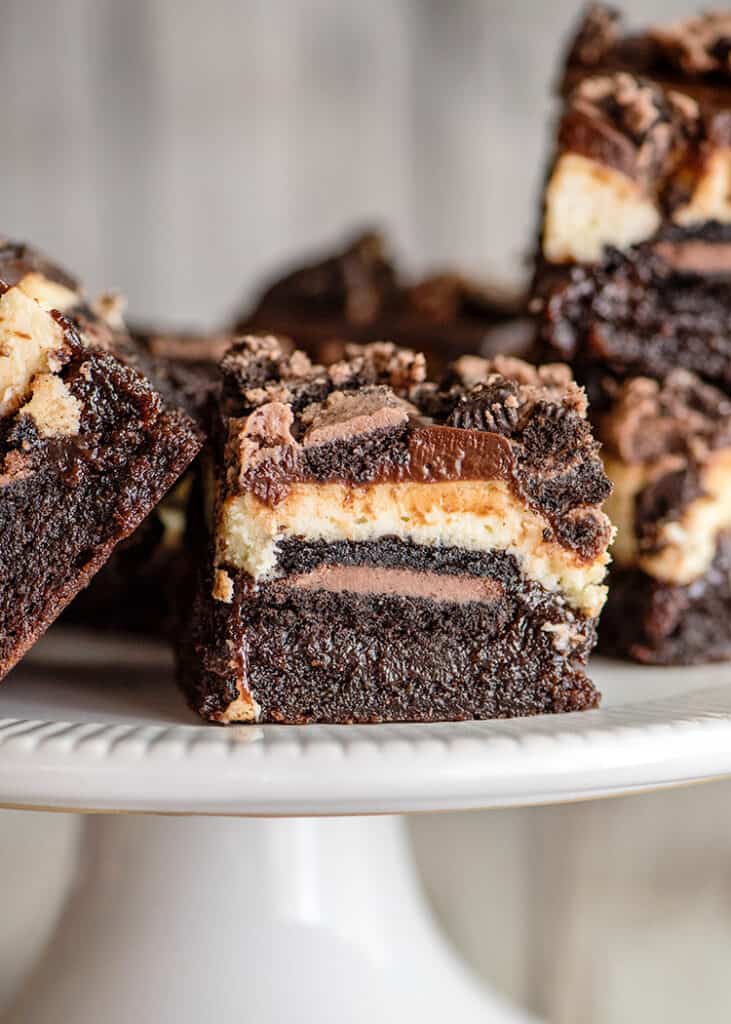 a layered brownie bar on a white plate with other bars around it