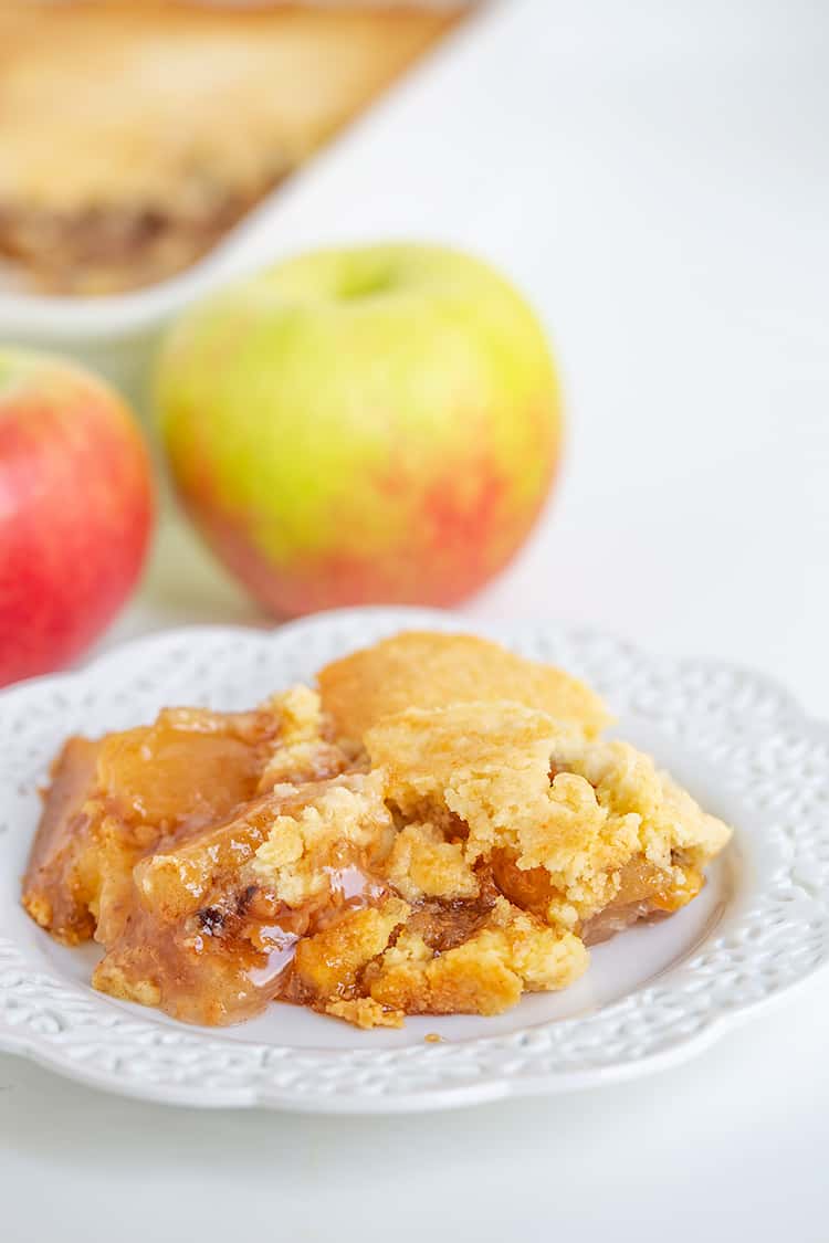 plate full of dump cake with apples behind it and a baking pan