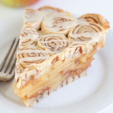 slice of cinnamon roll apple pie on a white plate with a fork