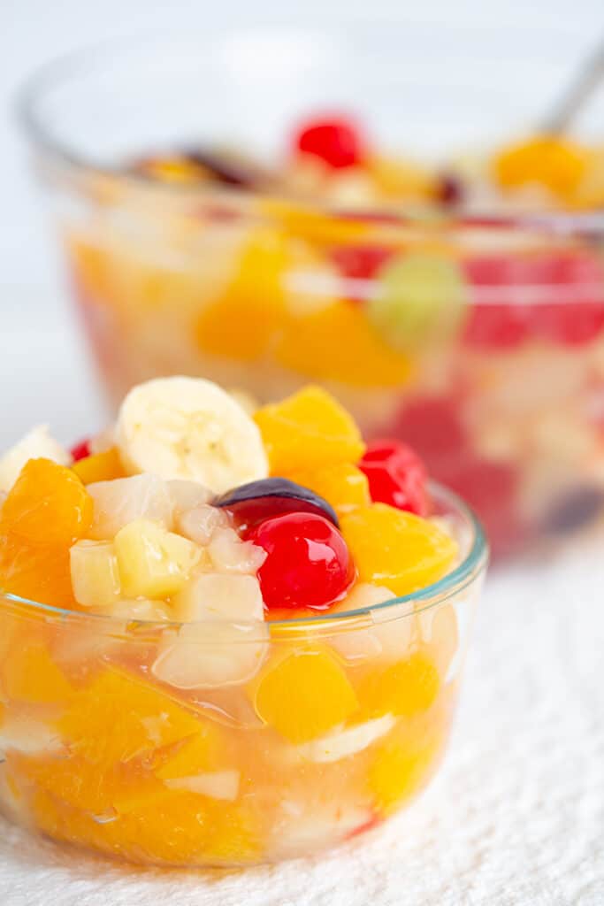 small glass bowl of fruit salad with a large glass bowl of in the background
