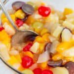 bowl full of fruit salad with a serving spoon in it