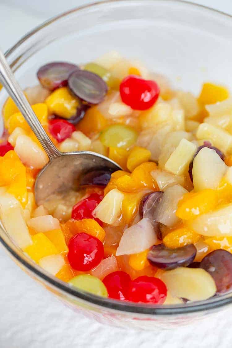 bowl full of fruit salad with a serving spoon in it