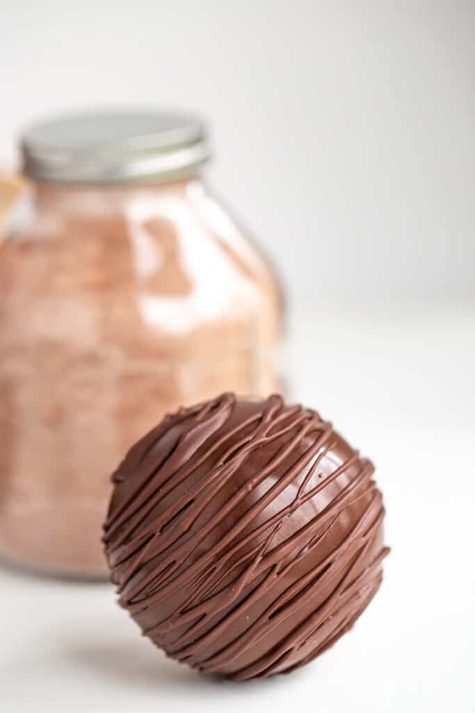 hot chocolate bomb with a jar of hot cocoa mix behind it