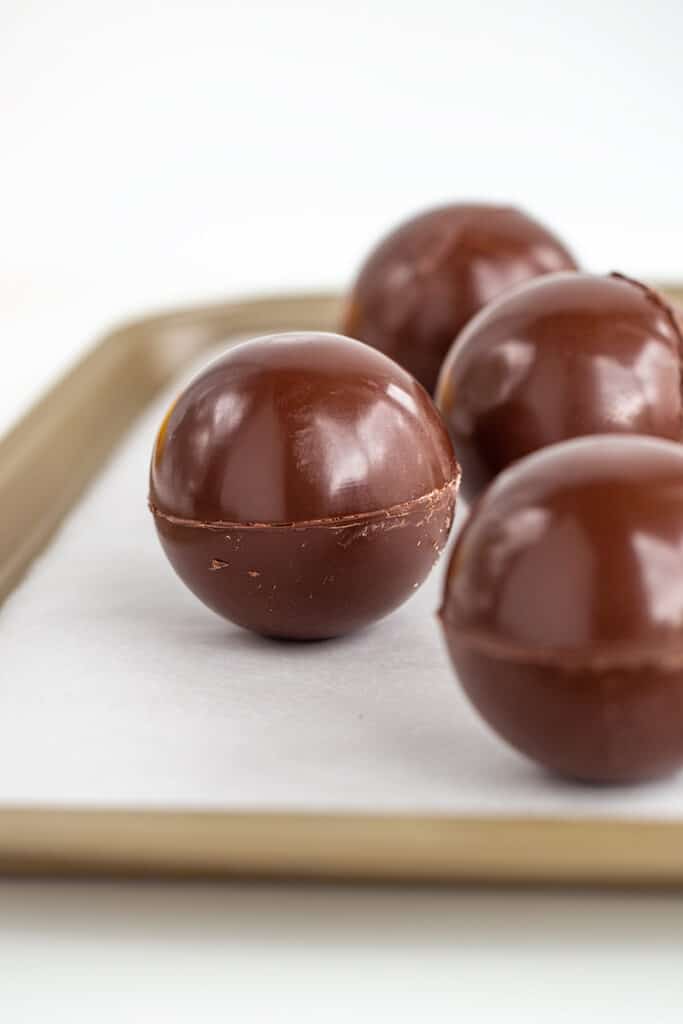 Sealed hot cocoa bombs on a pan with parchment paper