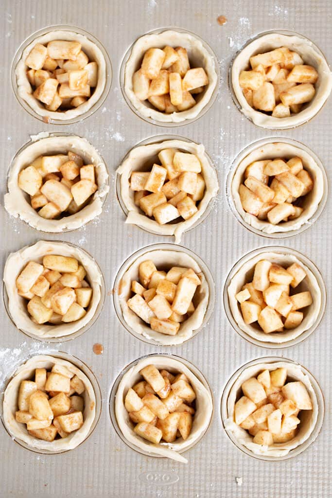 cupcake pan full of pie crust and apple pie filling