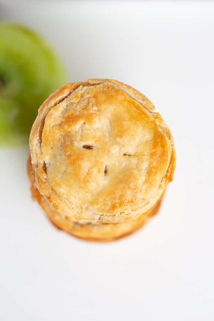 overhead photo of the top of a mini apple pie with a green apple beside it