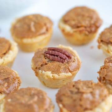 showing the middle pecan tassie with a whole pecan on it on a white surface