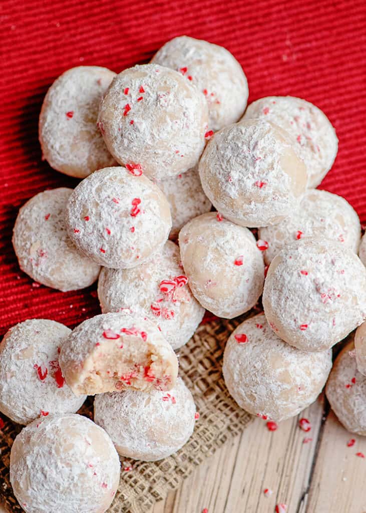 overhead photo of lots of snowball cookies on a red linen and a wooden surface