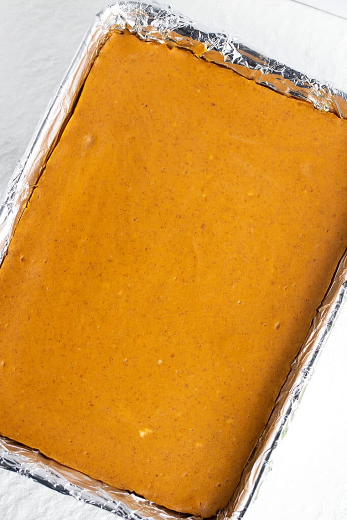 pan of pumpkin cheesecake bars with a white surface