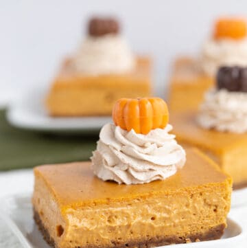 slice of pumpkin cheesecake bars on a white square plate