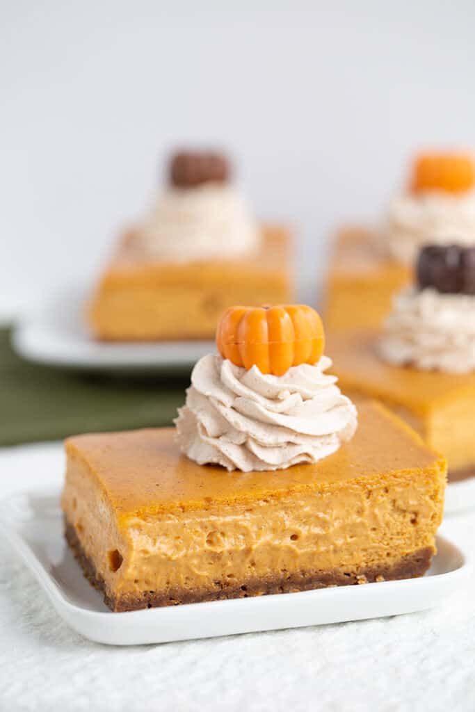slice of pumpkin cheesecake bars on a white square plate