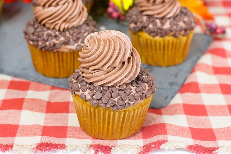 horizontal photo of a cupcake on a red checkered fabric with 2 more cupcakes behind it