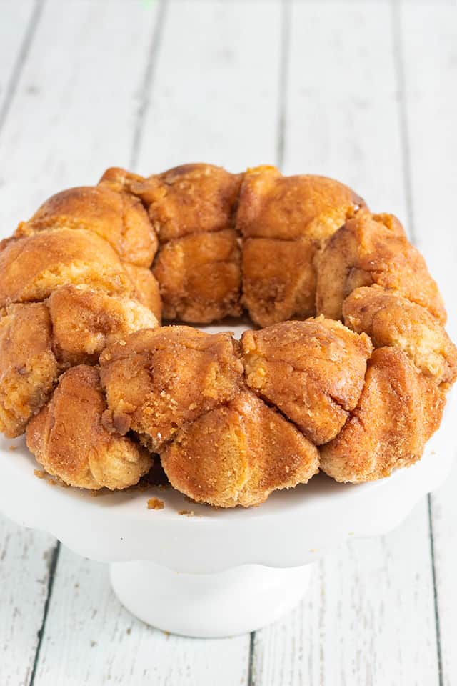 monkey bread on a white cake plate on a white wooden surface