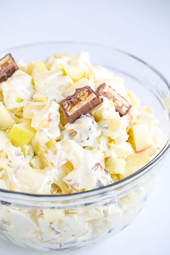 glass bowl full of apple snickers salad with a slice of snickers on top